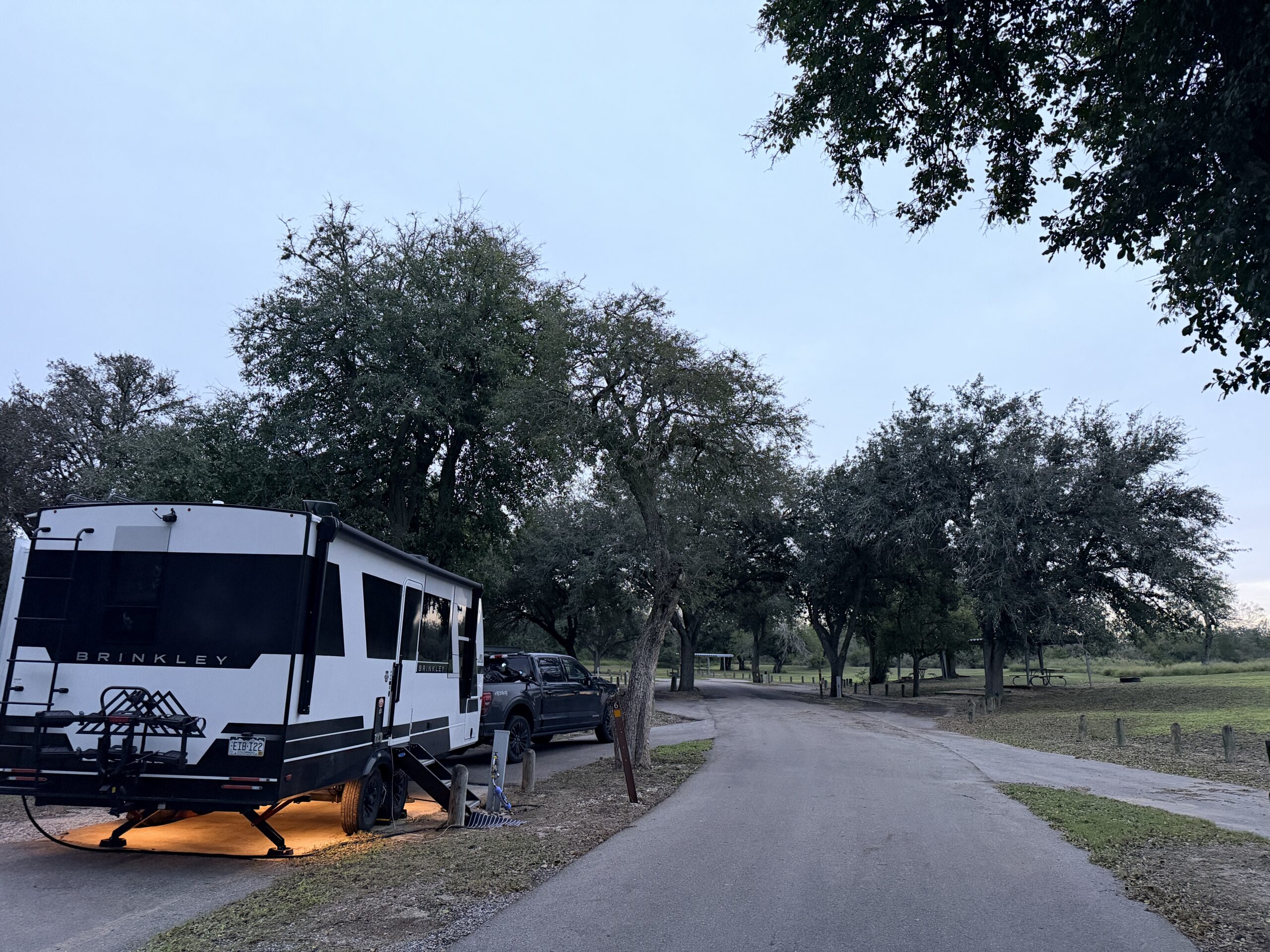 The Brinkley trailer with its underglow lights on at a shady oak lined campsite at Lake Corpus Christi.