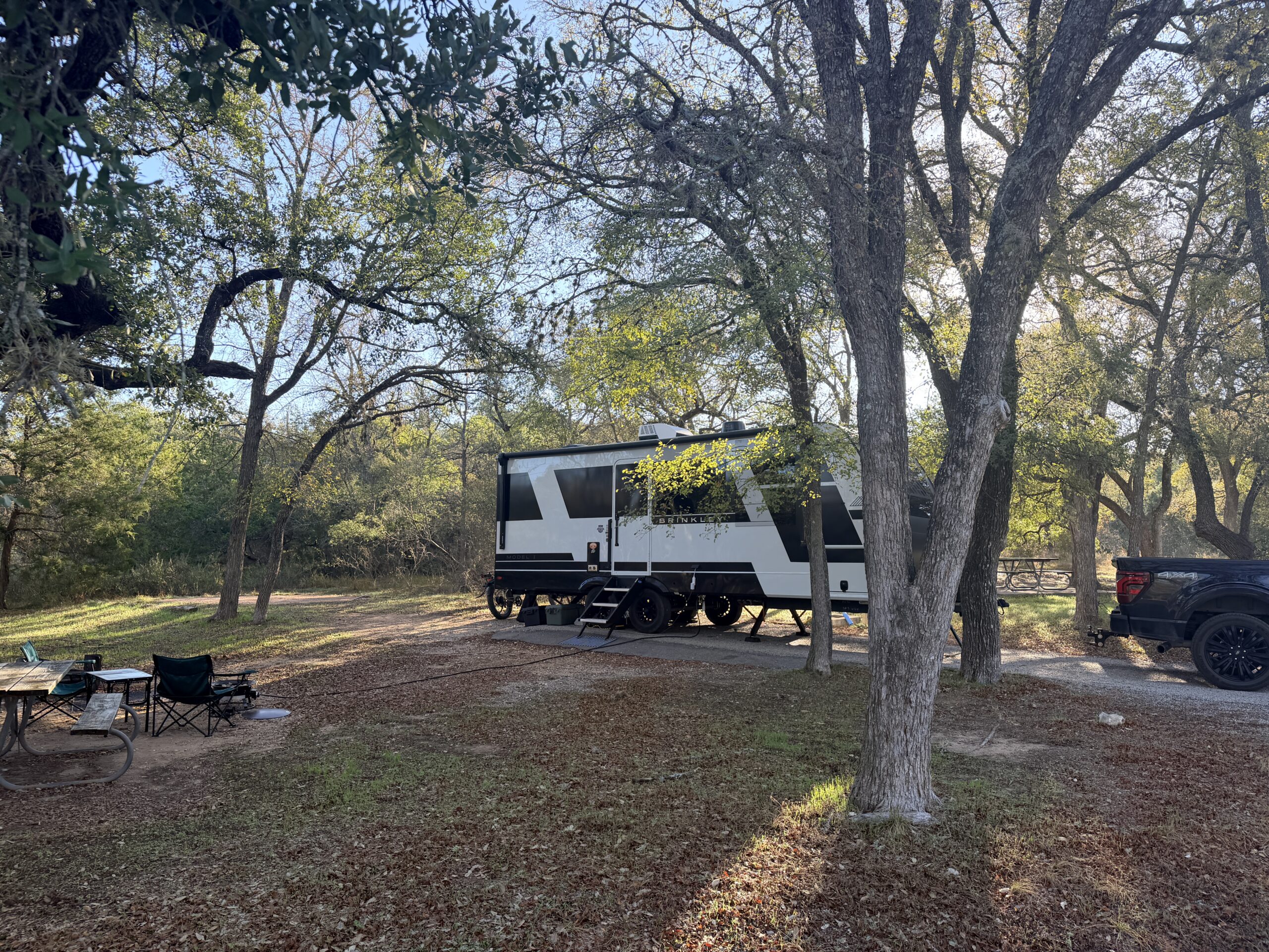 The Brinkley trailer parked at a shaded, wooded campsite at McKinney Falls State Park, Texas.